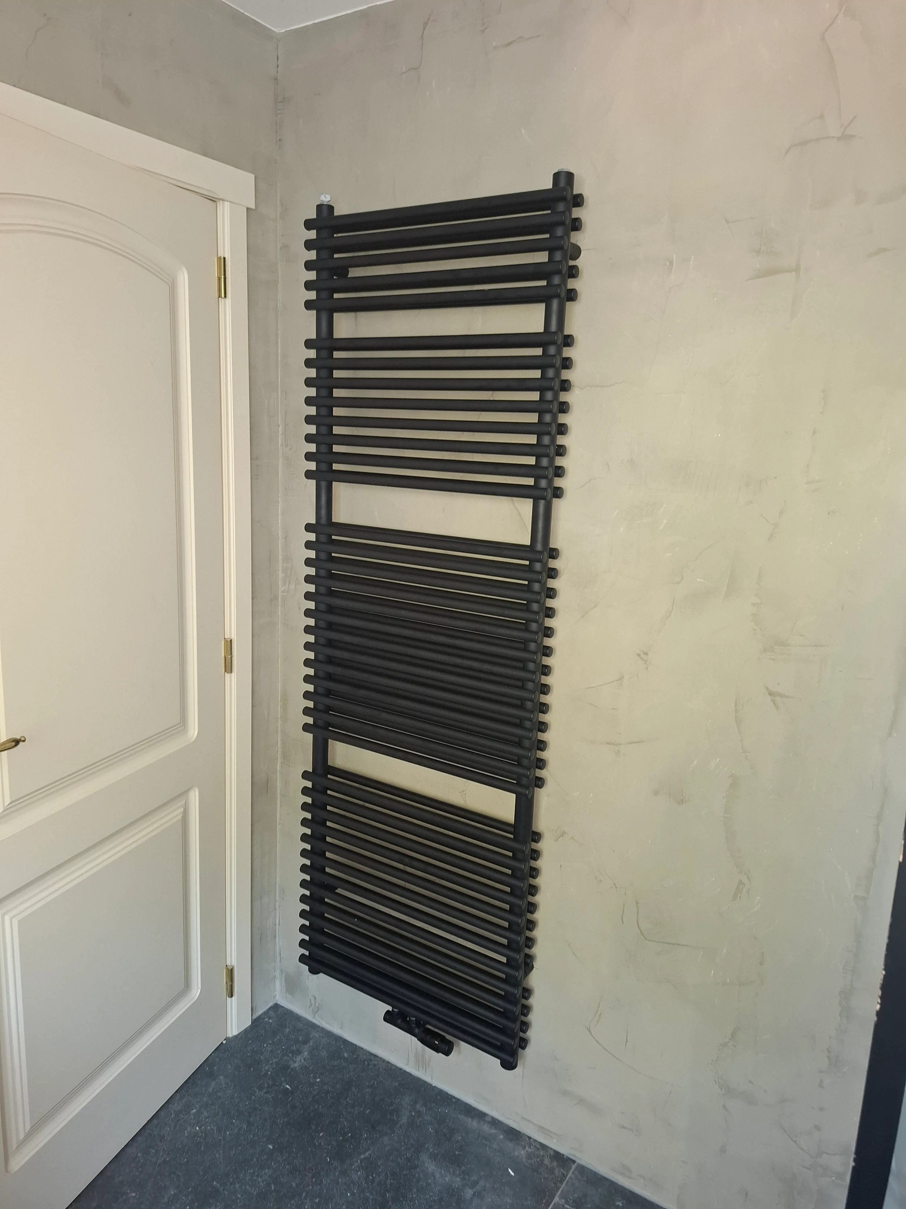 Geïnstalleerde zwarte handdoekradiator aan muur