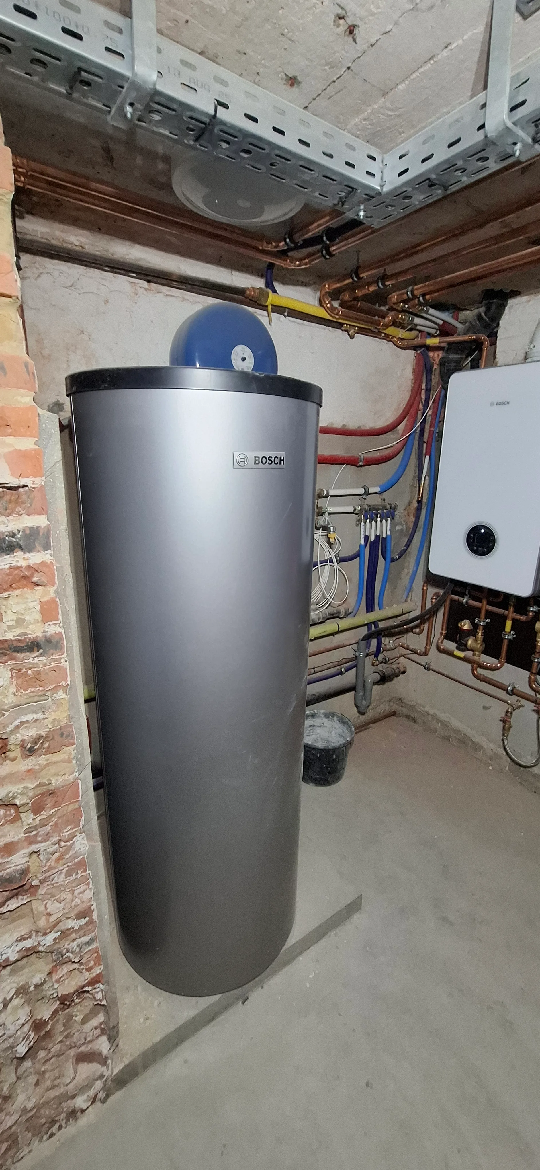 Een warmwaterboiler geplaatst in een technische ruimte met leidingen