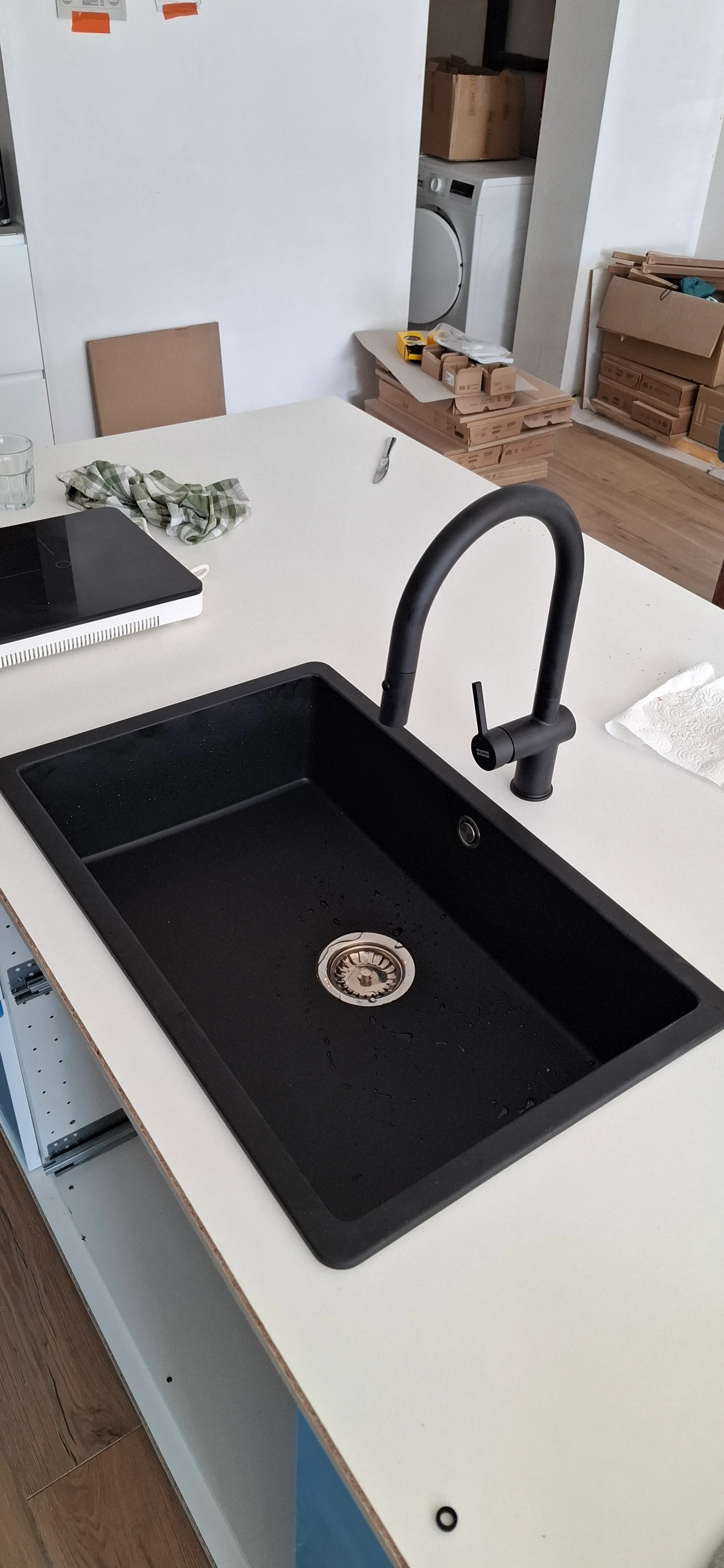 Zwarte keukenstaaf met spoelbak en moderne kraan op een wit aanrecht