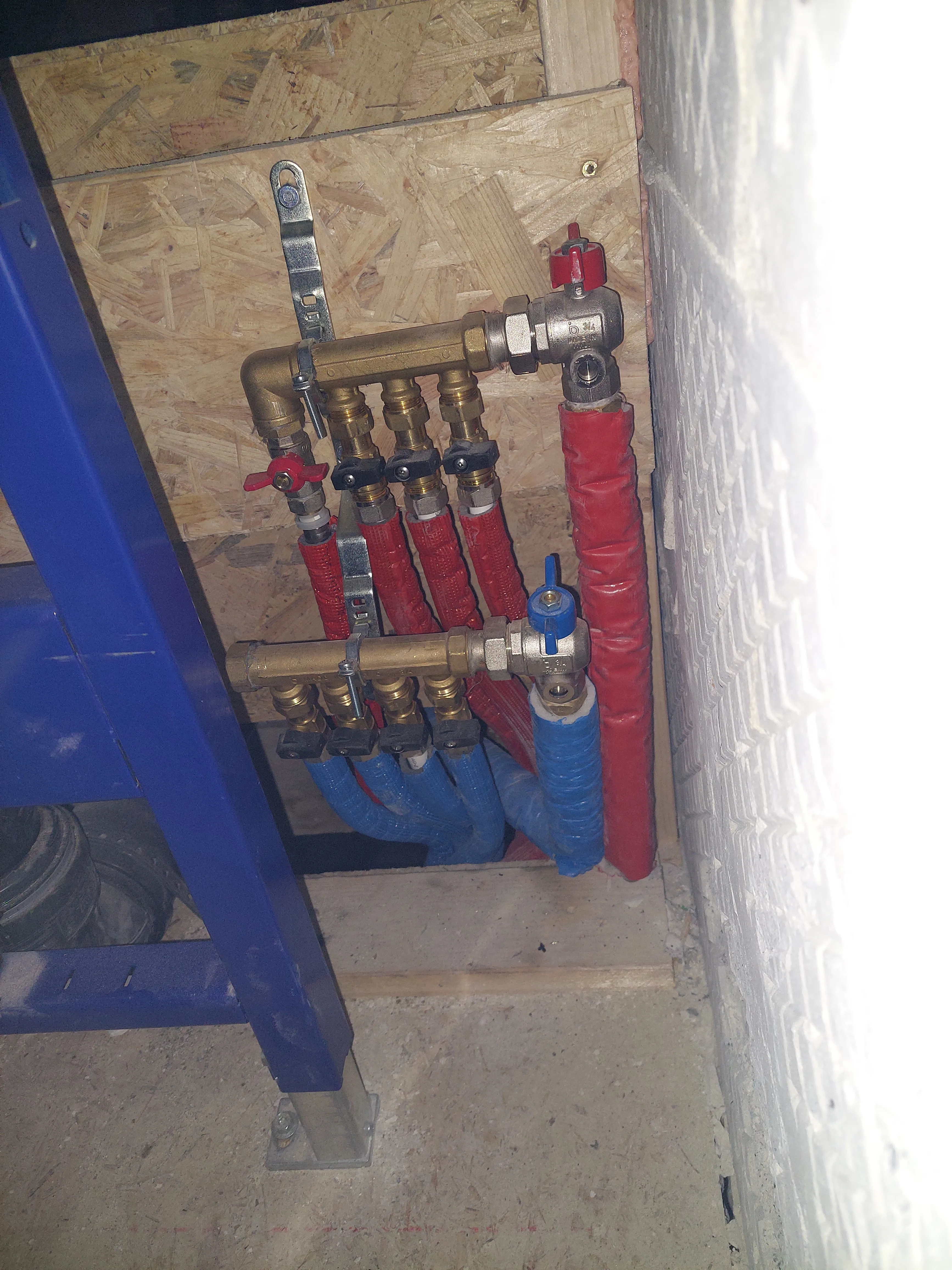 Piping system for heating installation with red and blue hoses, valves, and connections