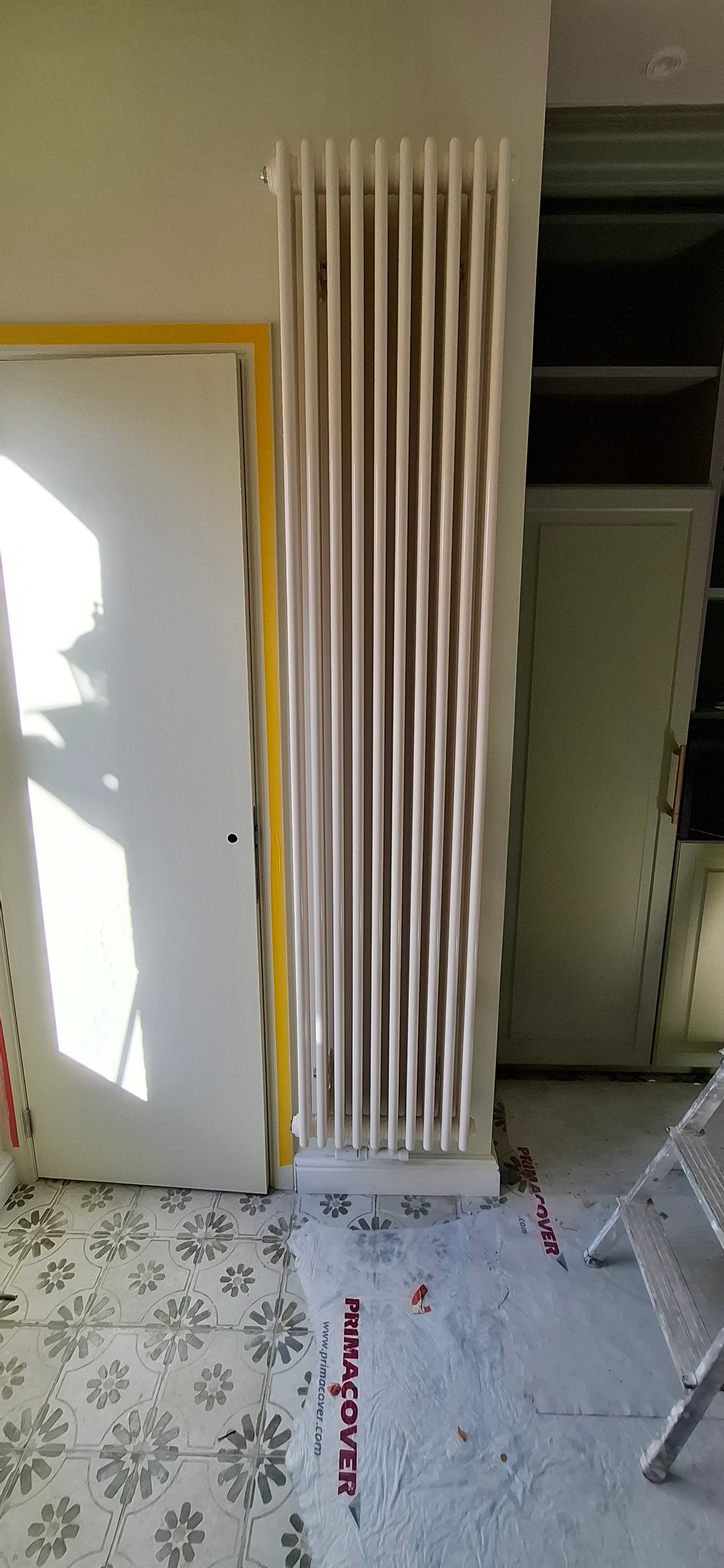 Moderne radiator geplaatst tegen een muur met lichtinval in een gerenoveerde ruimte