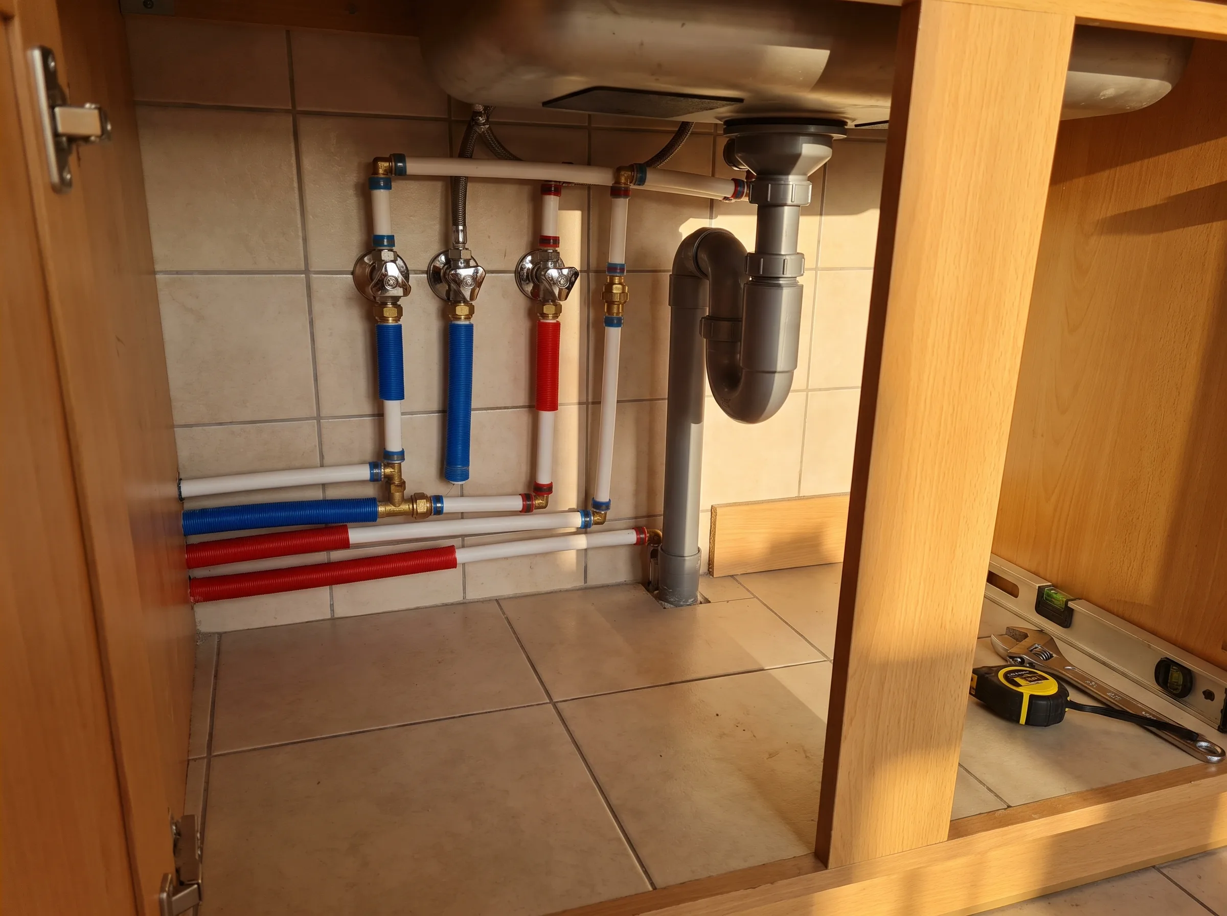 Sanitaire leidingen onder de gootsteen met waterafvoer en afsluiters