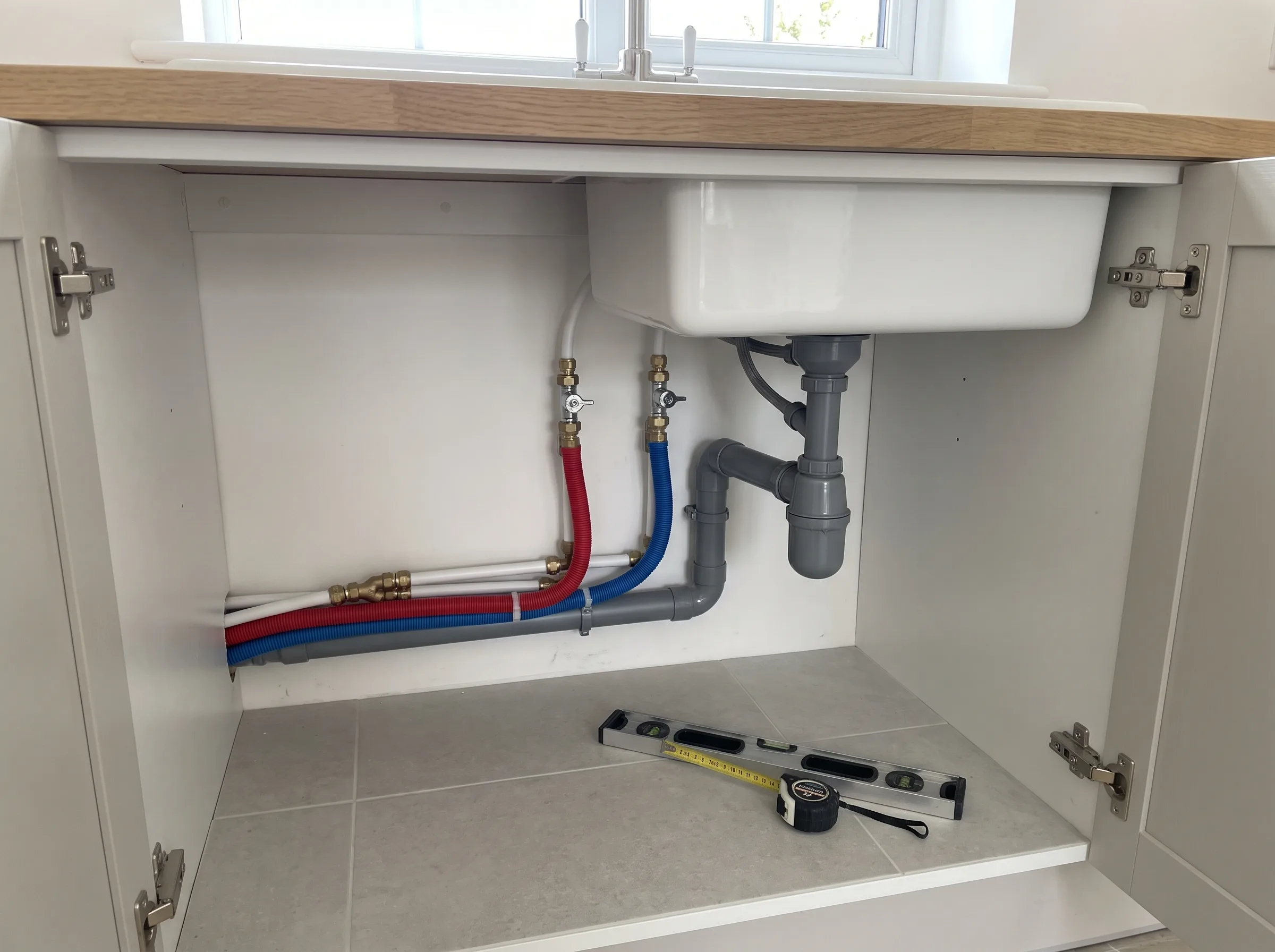 Onderbouw van een gootsteen met leidingen en afvoerinstallatie