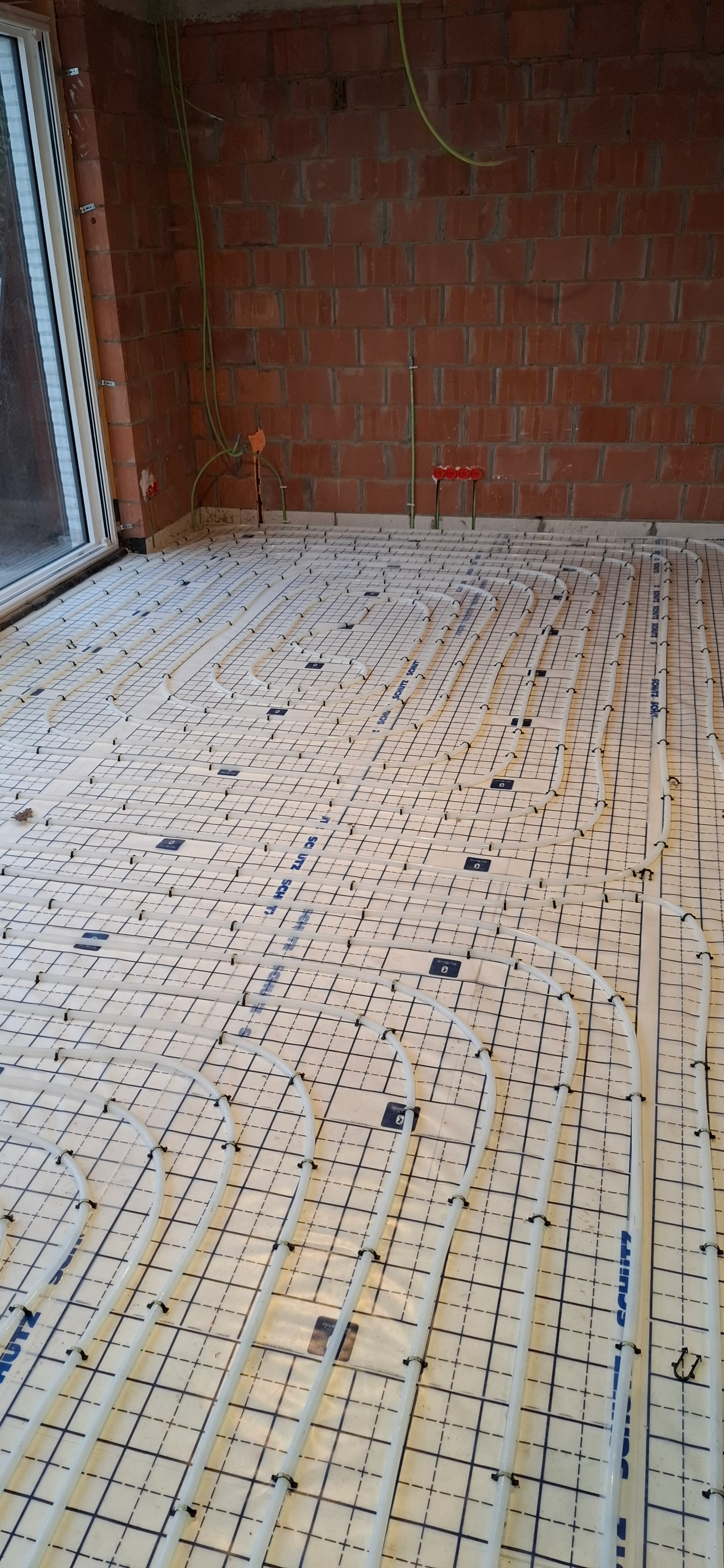 Vloerverwarming installatie met leidingen op de vloer in een ruimte met metselwerk